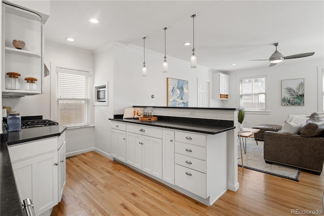 kitchen with light wood finished floors, open floor plan, a peninsula, and dark countertops