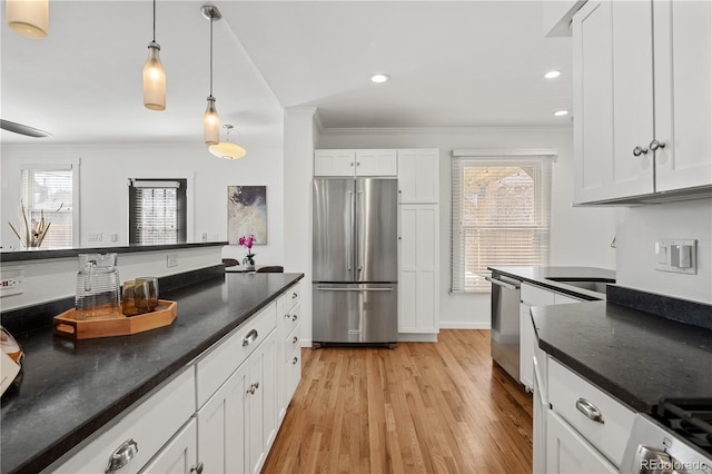 kitchen featuring ornamental molding, white cabinetry, stainless steel appliances, light wood-style floors, and hanging light fixtures