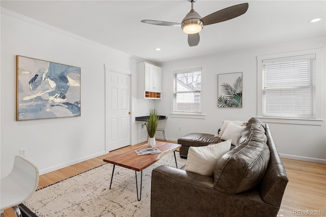 living room with light wood-style flooring, ornamental molding, baseboards, and ceiling fan