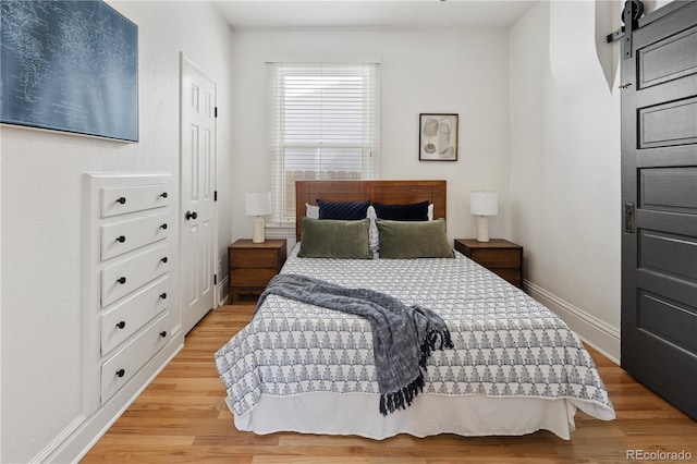 bedroom featuring a barn door, wood finished floors, and baseboards