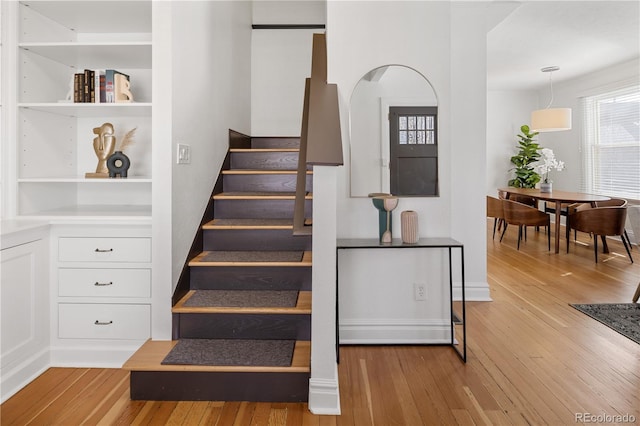 staircase with built in shelves and wood-type flooring