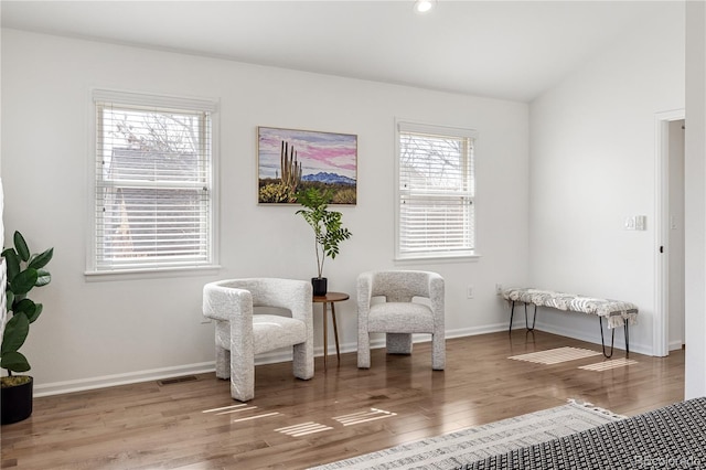 sitting room with visible vents, baseboards, wood finished floors, and vaulted ceiling