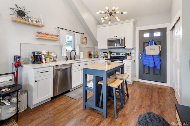 kitchen featuring dark wood-style floors, appliances with stainless steel finishes, white cabinetry, and a sink