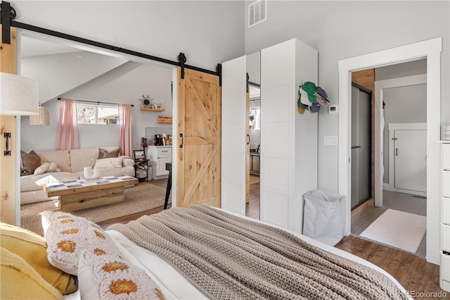 bedroom with visible vents, a barn door, and wood finished floors