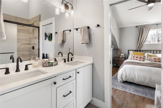 ensuite bathroom with a sink, wood finished floors, a stall shower, and a ceiling fan