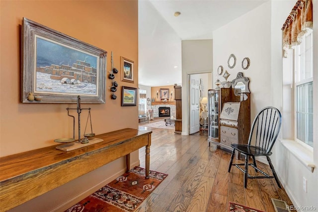 corridor featuring vaulted ceiling, light hardwood / wood-style flooring, and a wealth of natural light