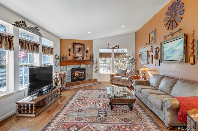 living room featuring a stone fireplace, lofted ceiling, and hardwood / wood-style floors