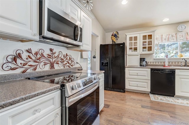 kitchen featuring white cabinetry, light wood-type flooring, black appliances, vaulted ceiling, and sink