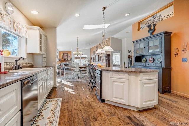 kitchen with sink, light hardwood / wood-style flooring, white cabinetry, and pendant lighting