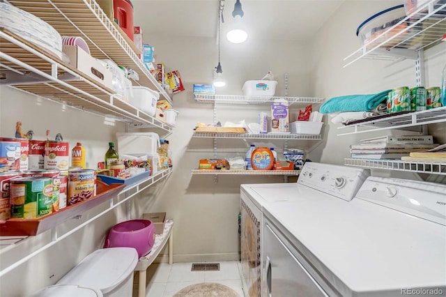 clothes washing area featuring light tile patterned flooring and washing machine and clothes dryer