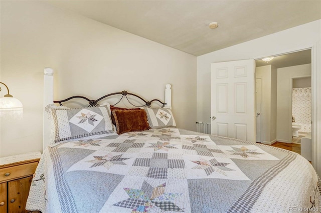 bedroom featuring hardwood / wood-style floors, vaulted ceiling, and ensuite bathroom