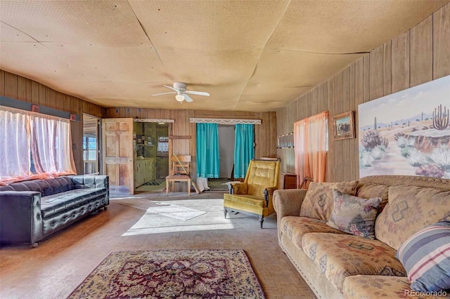 living room with a textured ceiling, a healthy amount of sunlight, ceiling fan, and wood walls