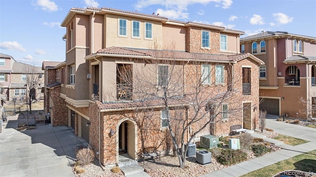 view of front of home with stucco siding, central air condition unit, driveway, and a tiled roof