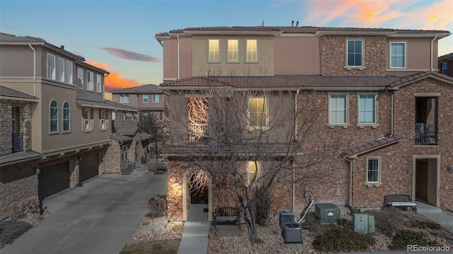 view of front of home with stucco siding, a garage, driveway, and a tiled roof