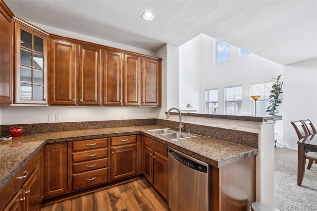 kitchen with a sink, dark countertops, stainless steel dishwasher, and a peninsula