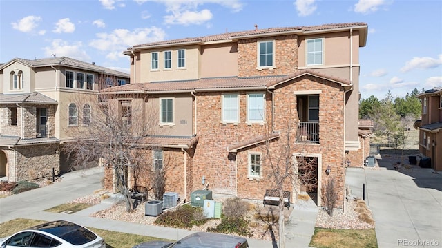 exterior space with cooling unit, concrete driveway, stucco siding, and a tiled roof