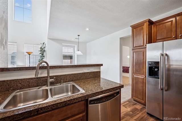 9374 Loggia St Unit D, Highlands Ranch, CO 80126 - kitchen with appliances with stainless steel finishes, a sink, dark countertops, dark wood-type flooring, and pendant lighting