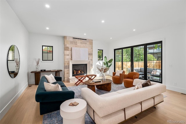 living room featuring a stone fireplace and light hardwood / wood-style floors