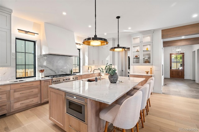 kitchen featuring a large island, light stone counters, backsplash, pendant lighting, and custom exhaust hood