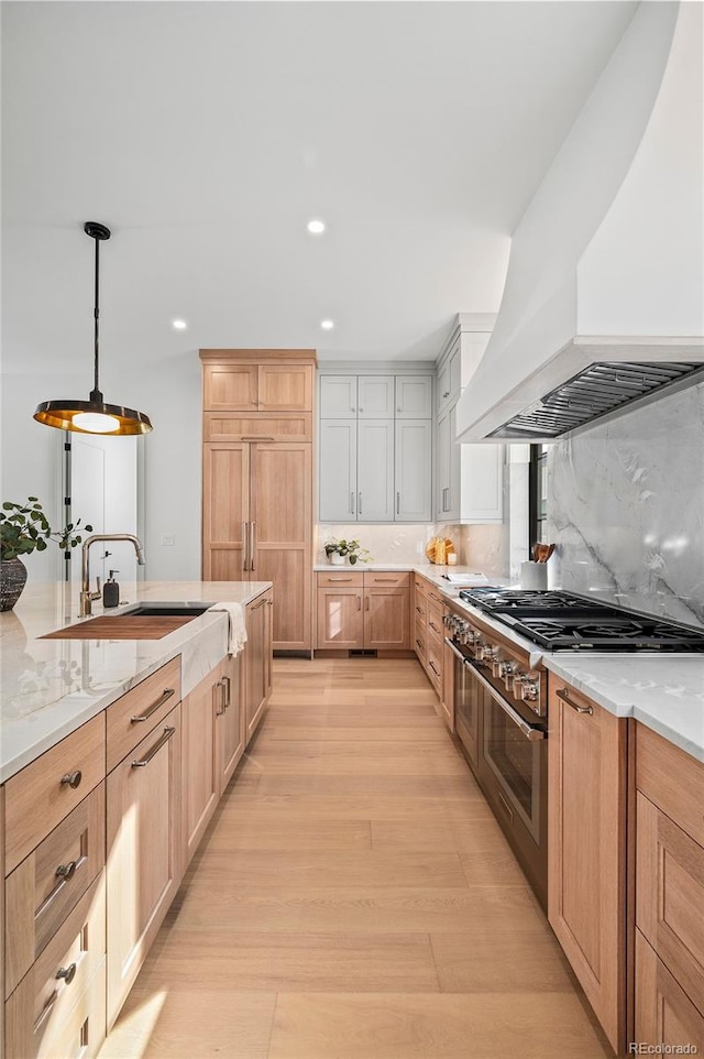 kitchen with pendant lighting, stainless steel gas stovetop, premium range hood, sink, and tasteful backsplash