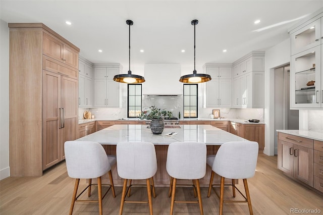 kitchen with light hardwood / wood-style floors, white cabinetry, tasteful backsplash, and a spacious island