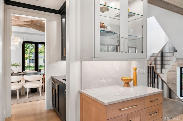 bar featuring light stone countertops, light wood-type flooring, lofted ceiling with beams, and backsplash