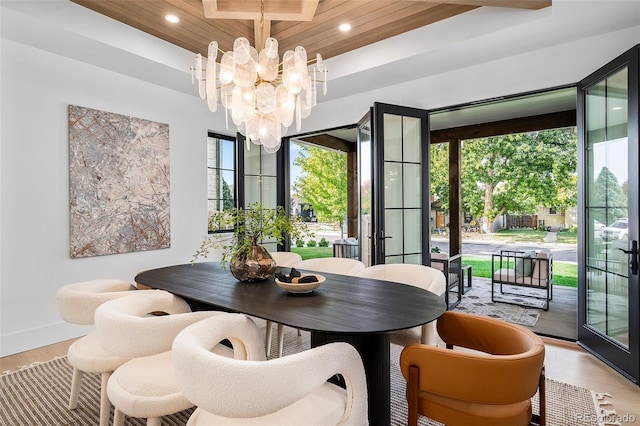 dining space with light hardwood / wood-style floors, an inviting chandelier, wood ceiling, and french doors