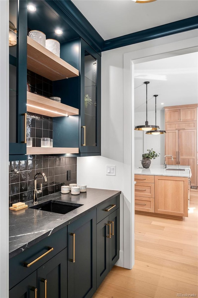 kitchen with pendant lighting, tasteful backsplash, sink, and light hardwood / wood-style flooring