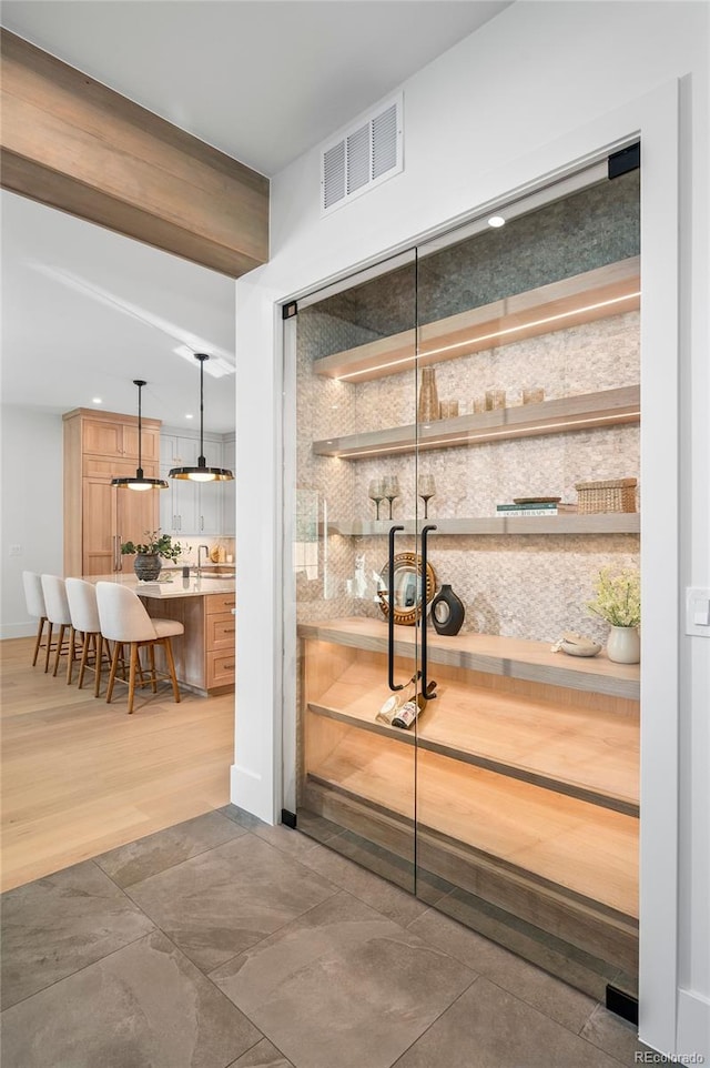 bar with decorative backsplash and decorative light fixtures