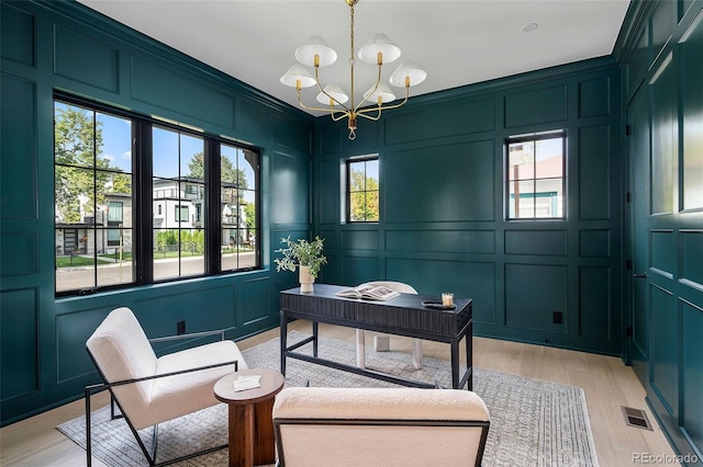 home office with a notable chandelier and light hardwood / wood-style flooring