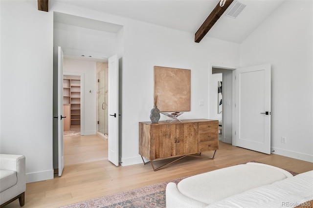 bedroom with lofted ceiling with beams, light hardwood / wood-style flooring, and a spacious closet