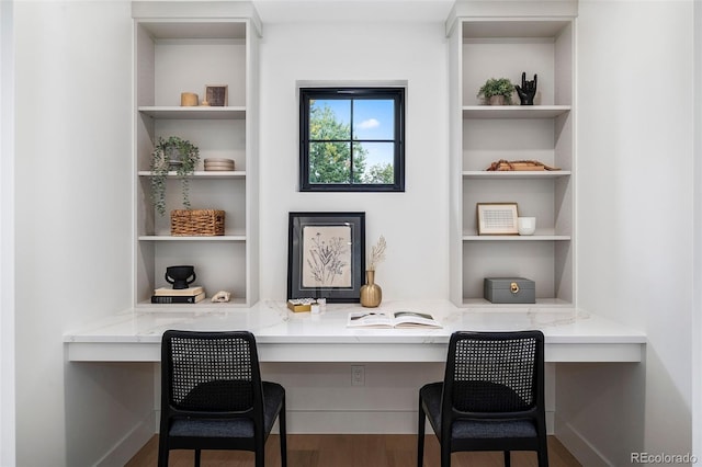 home office featuring dark hardwood / wood-style flooring and built in desk