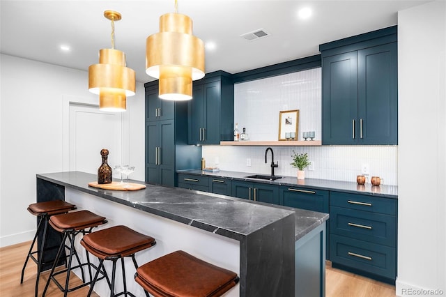 kitchen with a kitchen bar, blue cabinets, and sink