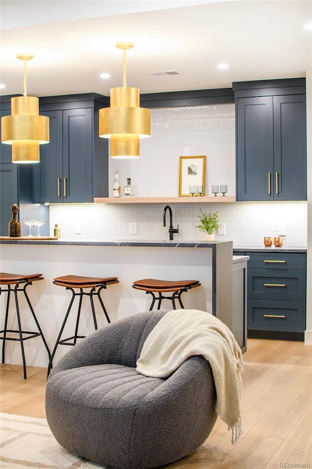 kitchen with a breakfast bar, blue cabinets, and light hardwood / wood-style flooring