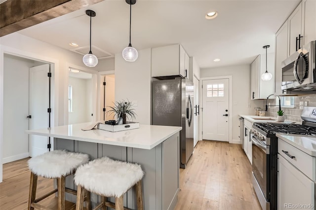 1120 Xenia St, Denver, CO 80220 - kitchen with a kitchen bar, light wood-style flooring, backsplash, stainless steel appliances, and light countertops