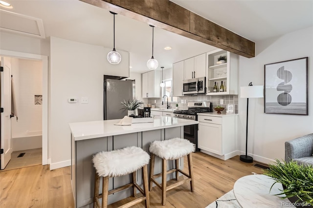 1120 Xenia St, Denver, CO 80220 - kitchen featuring light wood finished floors, backsplash, a kitchen breakfast bar, stainless steel appliances, and open shelves