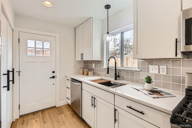 1120 Xenia St, Denver, CO 80220 - kitchen with light wood finished floors, a sink, stainless steel appliances, decorative light fixtures, and tasteful backsplash