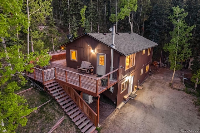 375 Castlewood Dr, Evergreen, CO 80439 - view of front of property with roof with shingles, a deck, a view of trees, and stairs