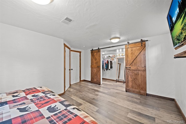375 Castlewood Dr, Evergreen, CO 80439 - unfurnished bedroom with a barn door, wood finished floors, a walk in closet, and a closet