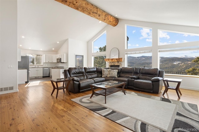 living room with a mountain view, beam ceiling, light wood-type flooring, and high vaulted ceiling