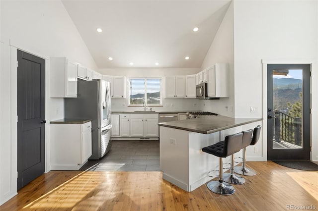 kitchen with white cabinets, a kitchen breakfast bar, sink, kitchen peninsula, and stainless steel appliances