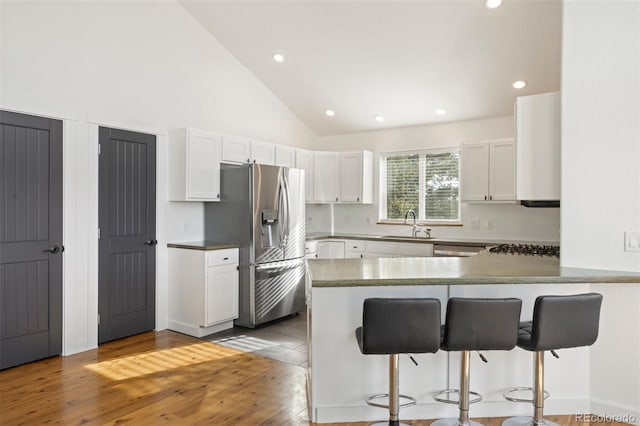 kitchen with kitchen peninsula, a breakfast bar, white cabinets, and stainless steel refrigerator with ice dispenser