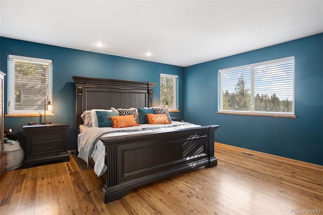 bedroom with light hardwood / wood-style flooring and multiple windows