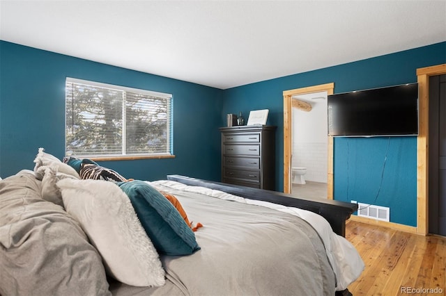 bedroom with hardwood / wood-style floors and ensuite bath