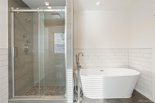 bathroom featuring tile patterned flooring, shower with separate bathtub, and tile walls