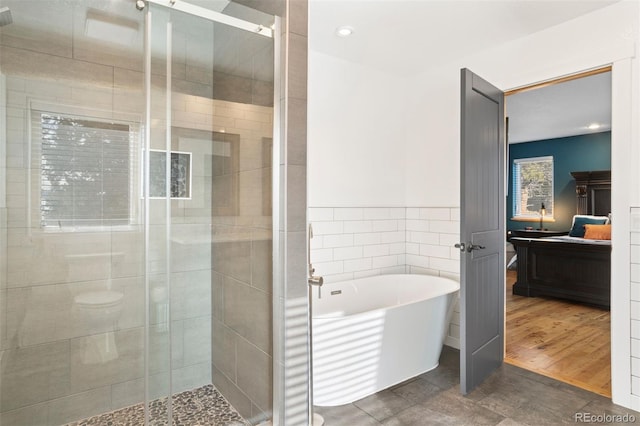 bathroom with plus walk in shower, tile patterned floors, and tile walls