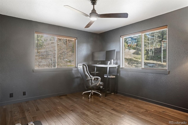 unfurnished office with hardwood / wood-style floors, ceiling fan, and a healthy amount of sunlight