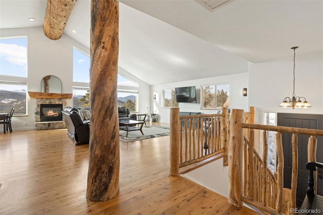 hall with beamed ceiling, light wood-type flooring, an inviting chandelier, and a wealth of natural light