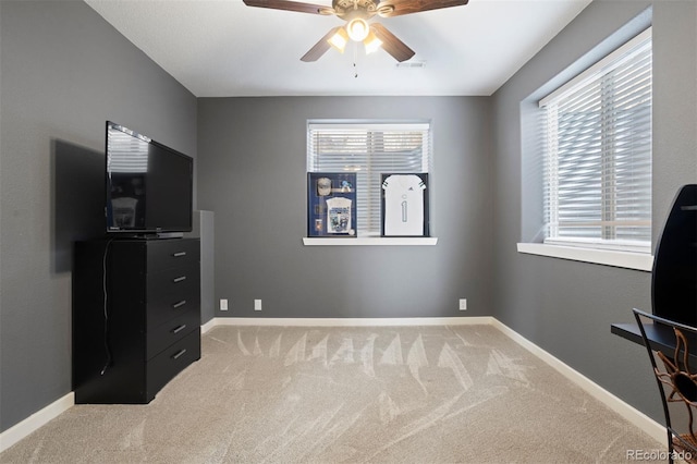 interior space with a wealth of natural light, light carpet, and ceiling fan