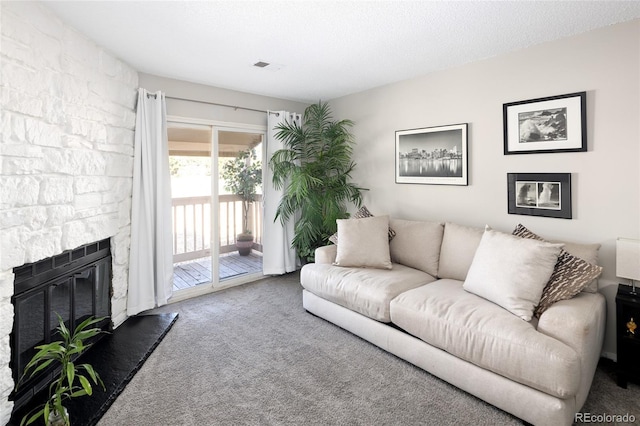 carpeted living room with a textured ceiling and a stone fireplace